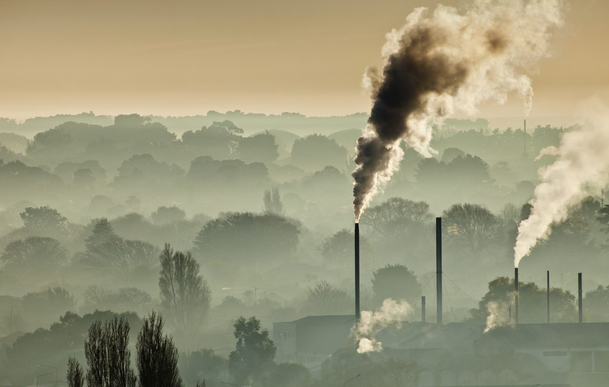 Factory chimneys belch smoke, winter smog makes it hard to see houses between trees, Christchurch, Canterbury, New Zealand